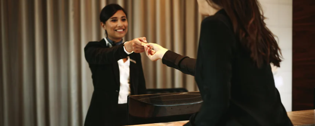 front desk staff at hotel hands guest a key